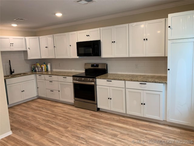 kitchen with black microwave, electric stove, a sink, and white cabinetry