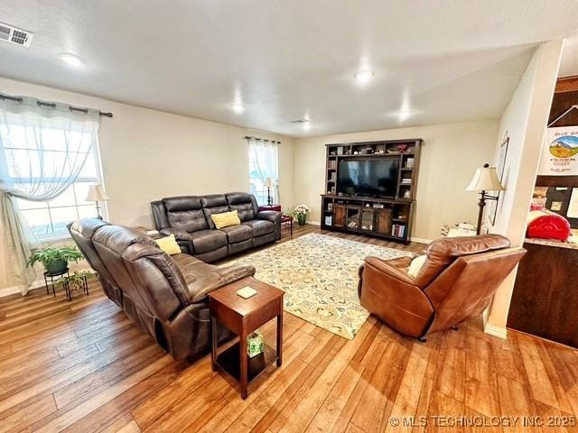 living room featuring light wood-style floors, baseboards, and visible vents