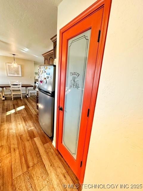 kitchen with freestanding refrigerator, a textured ceiling, and light wood finished floors