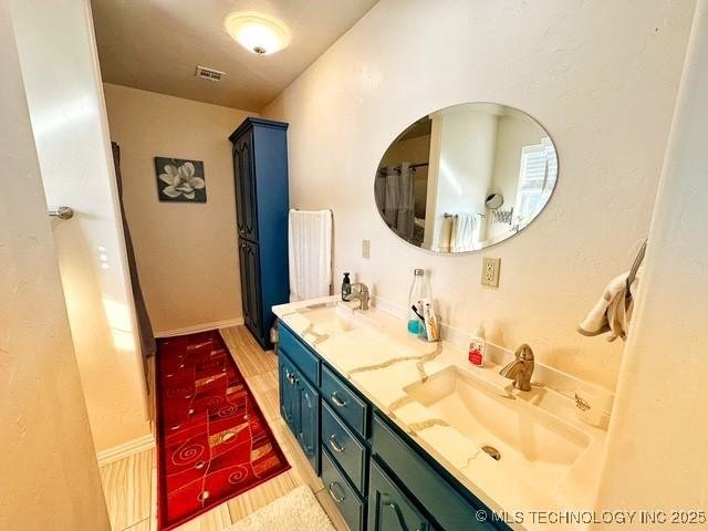 full bathroom with wood finished floors, a sink, visible vents, baseboards, and double vanity