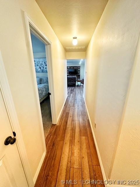 hallway featuring wood finished floors and baseboards