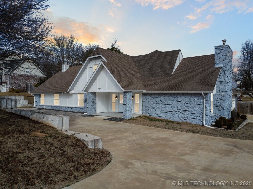 13433 S 125th E Ave, Broken Arrow, OK 74011 - view of front of home with stone siding, a chimney, concrete driveway, and roof with shingles