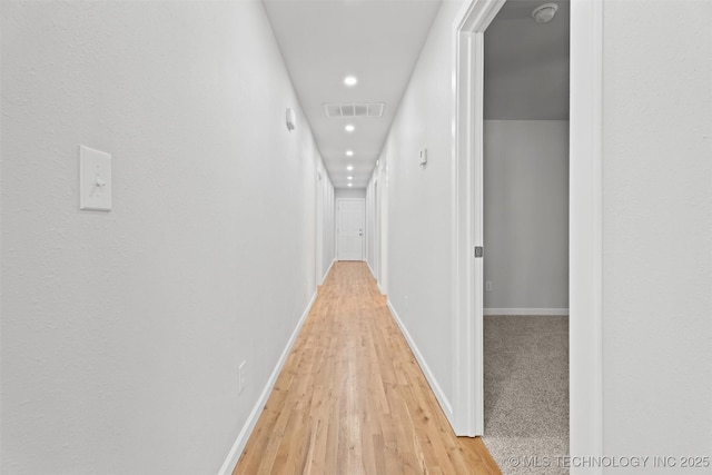 hall with visible vents, light wood finished floors, and baseboards