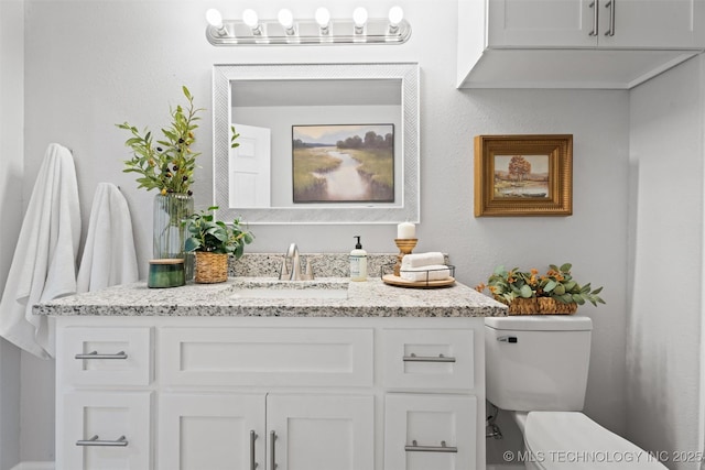 bathroom with a textured wall, vanity, and toilet