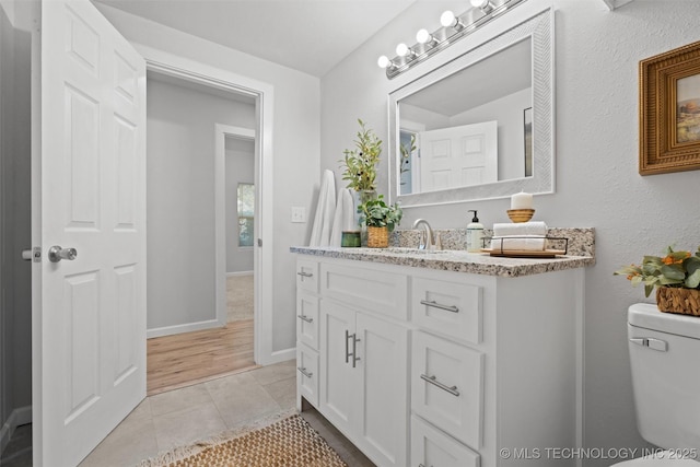 bathroom featuring toilet, vanity, baseboards, and tile patterned floors