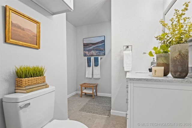 half bathroom with toilet, vanity, and baseboards