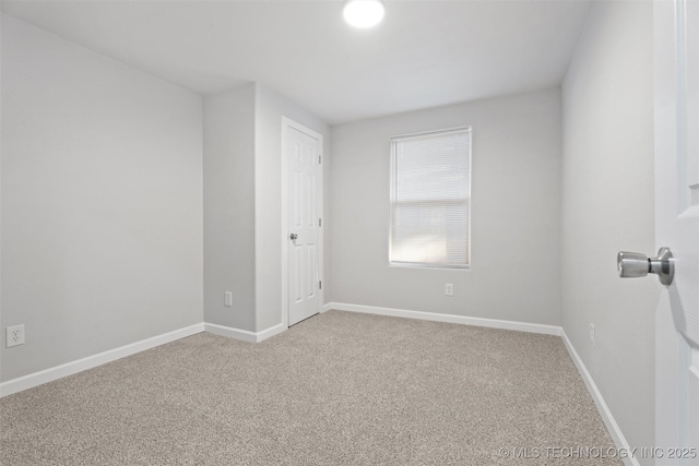 carpeted spare room featuring baseboards