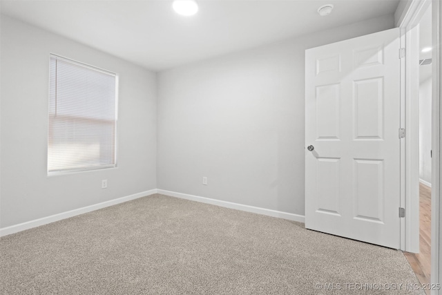 spare room featuring light carpet and baseboards