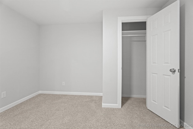 unfurnished bedroom featuring light carpet, a closet, and baseboards