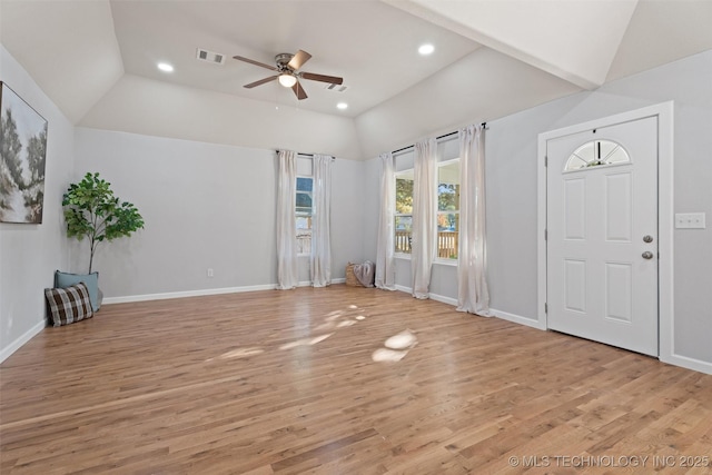 foyer entrance featuring visible vents, vaulted ceiling, and light wood-style flooring