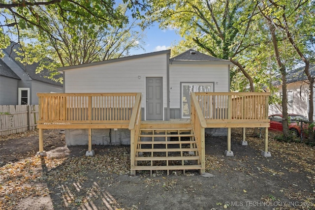 rear view of property featuring fence and a wooden deck