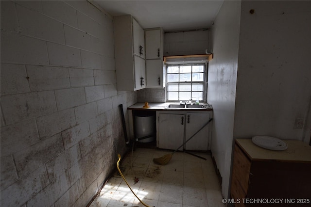 kitchen with light floors, white cabinets, and a sink