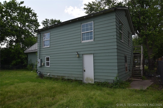 rear view of property featuring stairway and a lawn