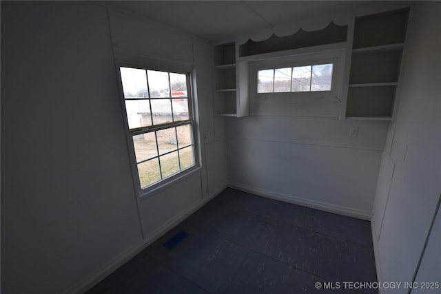 empty room featuring built in shelves, visible vents, and a healthy amount of sunlight