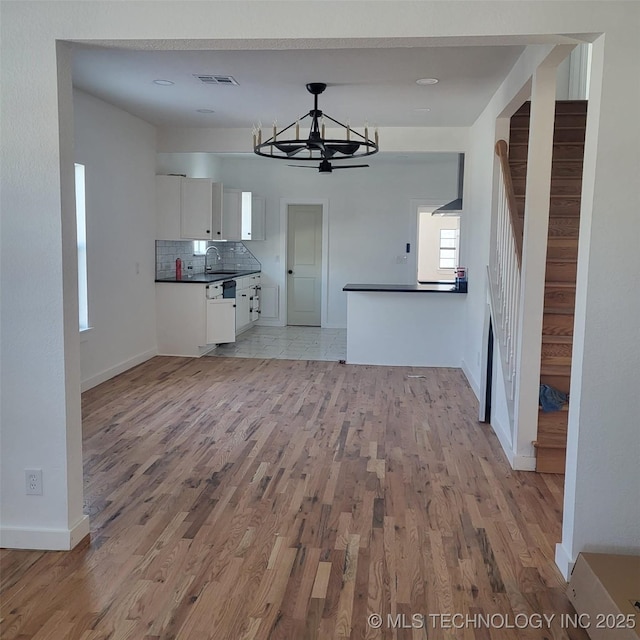 kitchen with tasteful backsplash, visible vents, white cabinets, dark countertops, and light wood-style floors