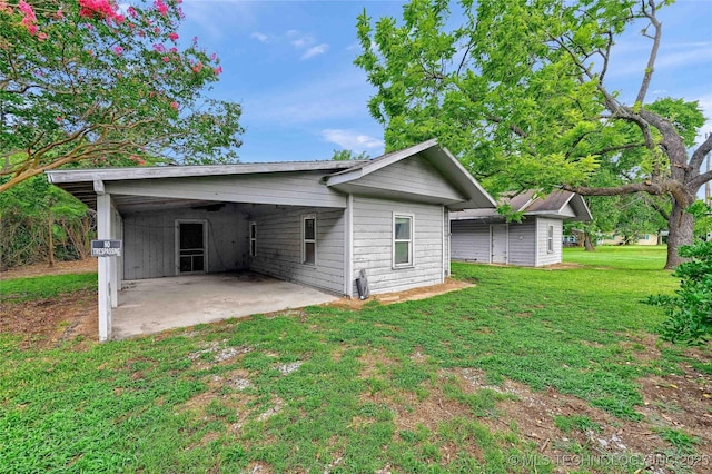 back of house featuring an attached carport and a lawn