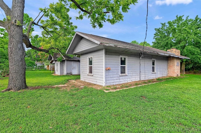 view of property exterior featuring an outbuilding, a lawn, and a chimney