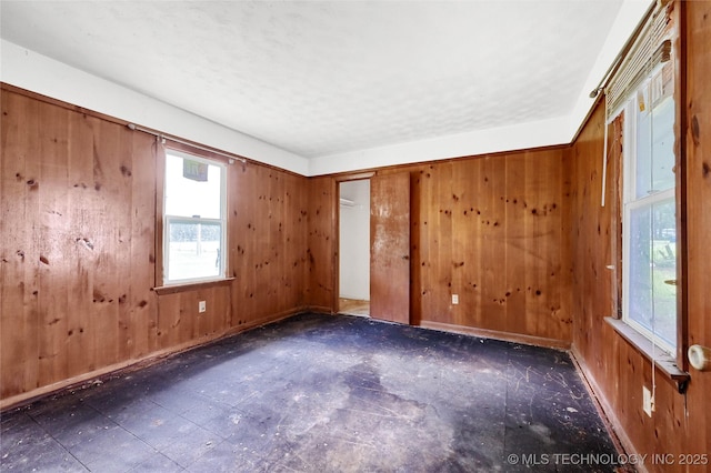 empty room featuring wood walls and baseboards