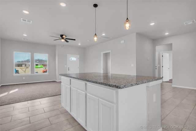 kitchen featuring white cabinets, visible vents, open floor plan, and dark stone counters