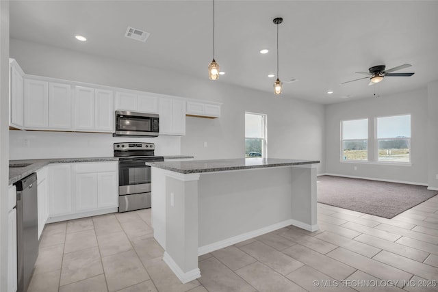 kitchen featuring stainless steel appliances, visible vents, white cabinets, open floor plan, and a center island