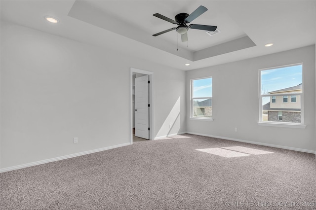 empty room featuring recessed lighting, a raised ceiling, light colored carpet, and baseboards