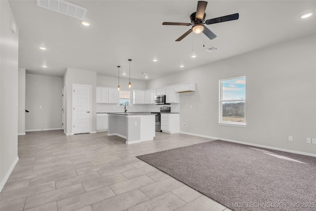 kitchen featuring a kitchen island, visible vents, white cabinetry, open floor plan, and appliances with stainless steel finishes