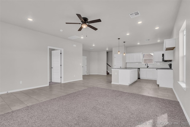 unfurnished living room with light tile patterned floors, recessed lighting, light colored carpet, a sink, and visible vents