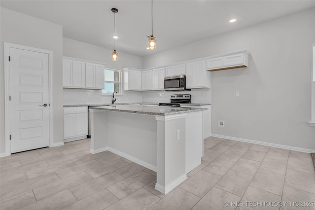 kitchen with a kitchen island, appliances with stainless steel finishes, light stone counters, decorative light fixtures, and white cabinetry