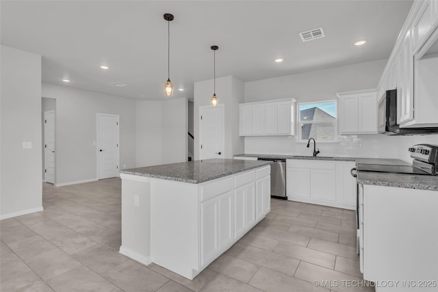 kitchen featuring stainless steel appliances, visible vents, white cabinets, a kitchen island, and a sink