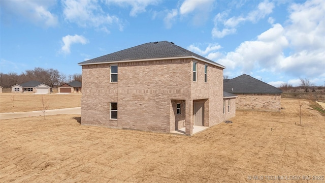 back of property featuring roof with shingles and brick siding