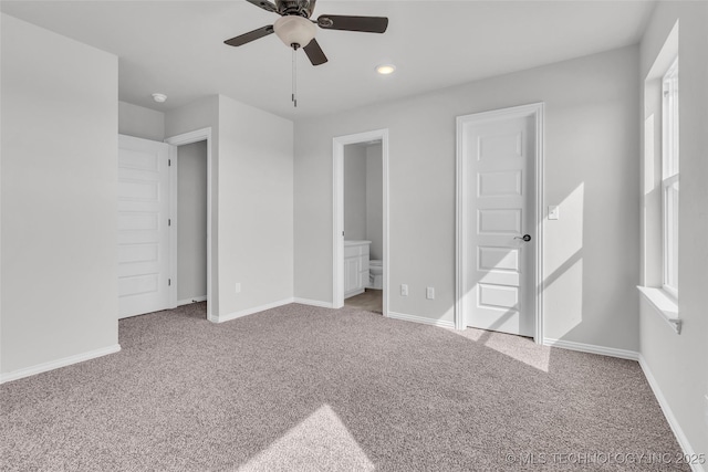 unfurnished bedroom with a ceiling fan, carpet flooring, connected bathroom, and baseboards