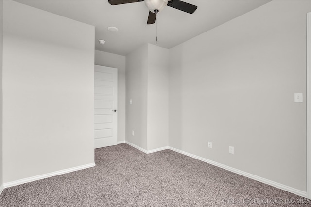 carpeted spare room featuring a ceiling fan and baseboards