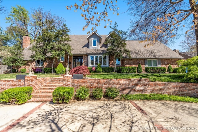 cape cod home featuring a front yard and brick siding