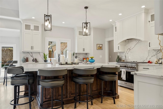 kitchen with light stone countertops, white cabinetry, glass insert cabinets, and stainless steel stove