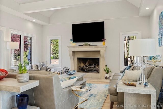 living room featuring lofted ceiling, a fireplace with raised hearth, wood finished floors, and recessed lighting