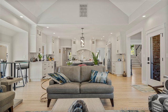 living room featuring recessed lighting, visible vents, stairway, light wood-style flooring, and high vaulted ceiling