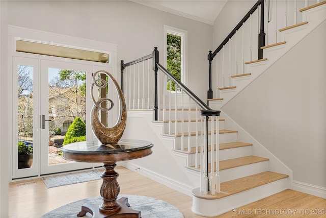 entrance foyer featuring light wood-style floors, baseboards, stairway, and crown molding