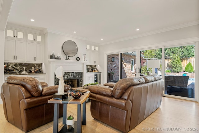 living room featuring a premium fireplace, light wood-style flooring, and crown molding