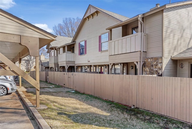 view of side of property featuring fence and a balcony