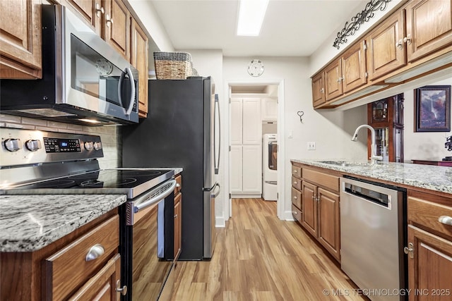 9114 S Urbana Ave Unit 9C, Tulsa, OK 74137 - kitchen featuring stainless steel appliances, light stone counters, brown cabinetry, and a sink