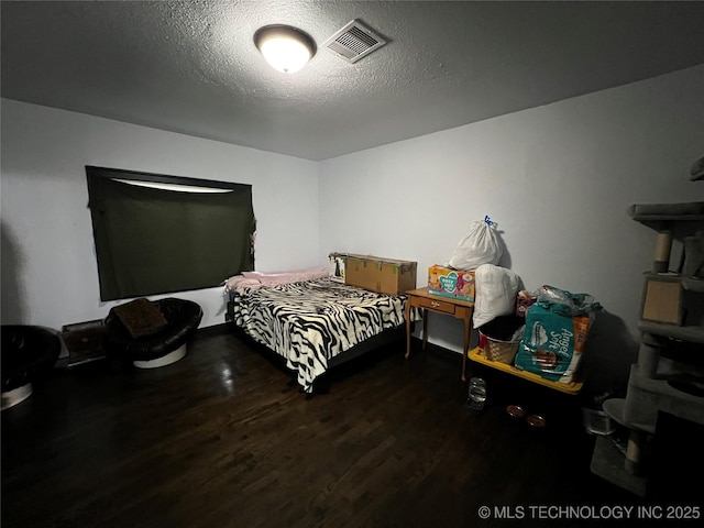 bedroom with dark wood-style floors, a textured ceiling, and visible vents