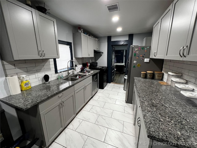 kitchen with marble finish floor, visible vents, appliances with stainless steel finishes, a sink, and dark stone countertops