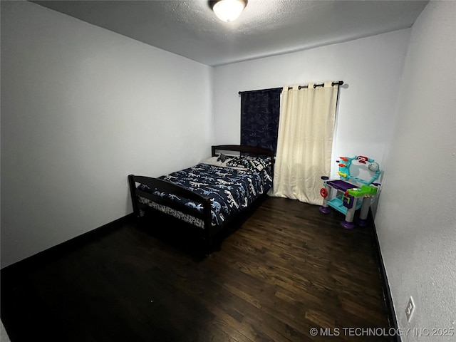 bedroom featuring a textured ceiling and dark wood-type flooring