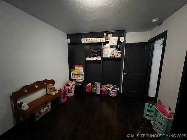 rec room featuring dark wood-type flooring and a textured ceiling