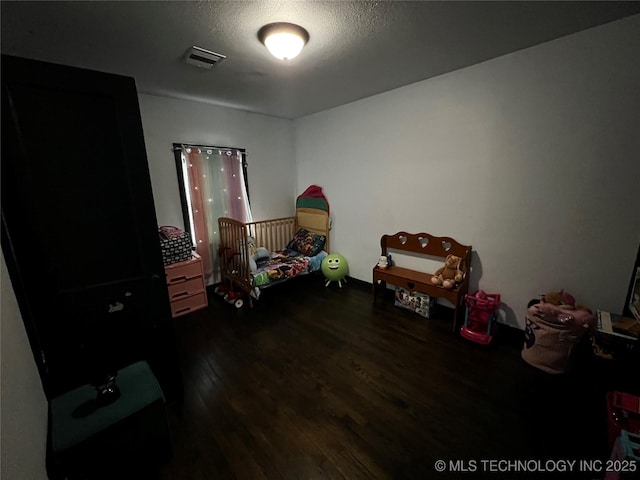 bedroom with a textured ceiling, dark wood finished floors, and visible vents