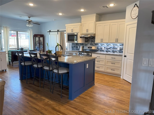1825 E 45th Pl, Sand Springs, OK 74063 - kitchen featuring a kitchen breakfast bar, visible vents, under cabinet range hood, a sink, and stainless steel appliances
