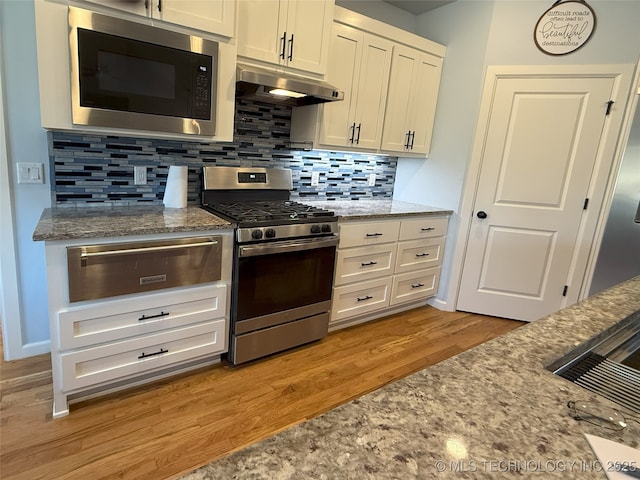 1825 E 45th Pl, Sand Springs, OK 74063 - kitchen with under cabinet range hood, a warming drawer, light stone counters, and appliances with stainless steel finishes