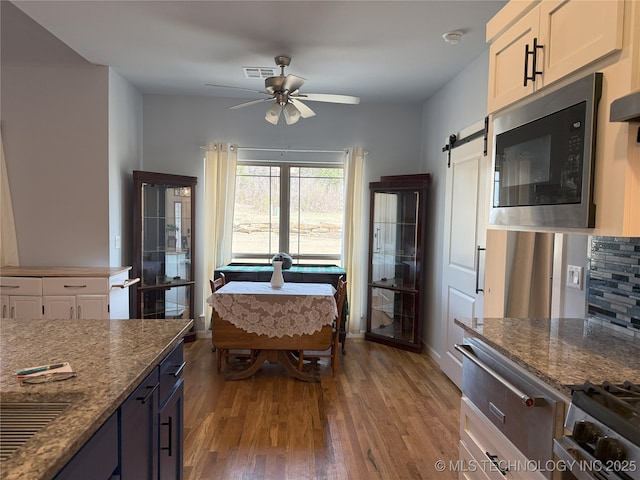 1825 E 45th Pl, Sand Springs, OK 74063 - kitchen with a ceiling fan, built in microwave, visible vents, dark stone counters, and wood finished floors