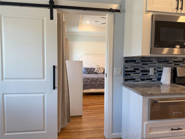 1825 E 45th Pl, Sand Springs, OK 74063 - kitchen with tasteful backsplash, a warming drawer, dark stone countertops, stainless steel microwave, and light wood finished floors