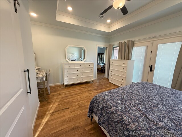 1825 E 45th Pl, Sand Springs, OK 74063 - bedroom featuring baseboards, recessed lighting, visible vents, a tray ceiling, and wood finished floors